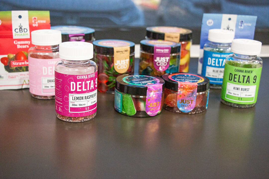 Wholesale CBD Gummies various brands standing on black office desk facing window