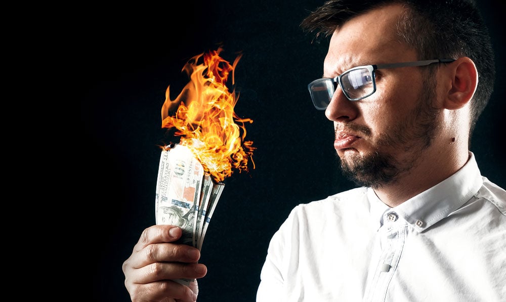 Man holding burning stack of cash