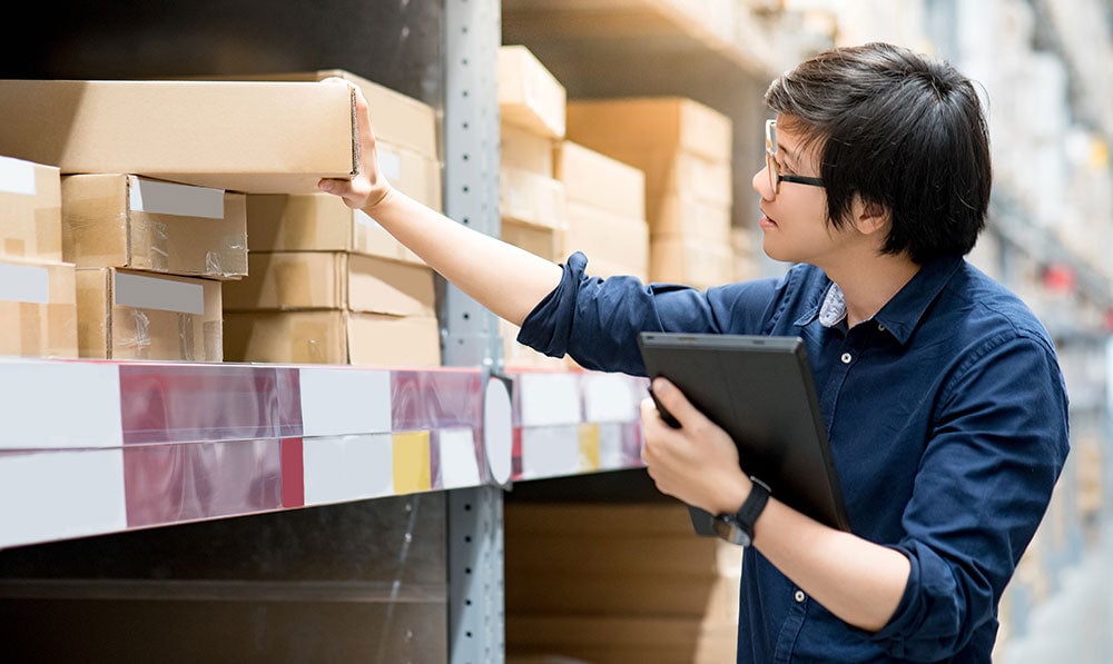 Man in blue shirt checking inventory inside warehouse
