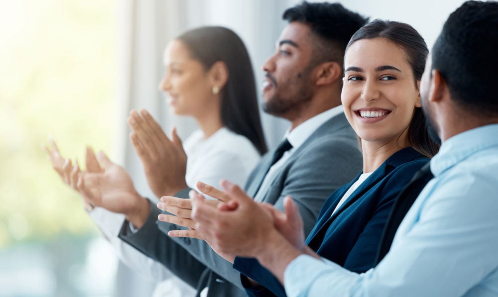 Smiling and clapping business people sitting together at a trade show