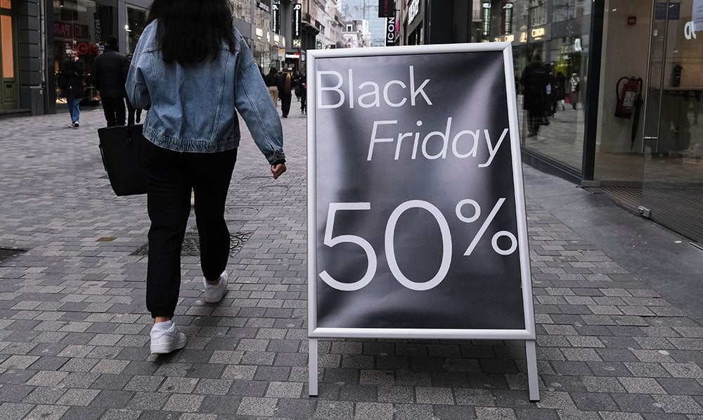 woman in jean jacket next to black friday sign