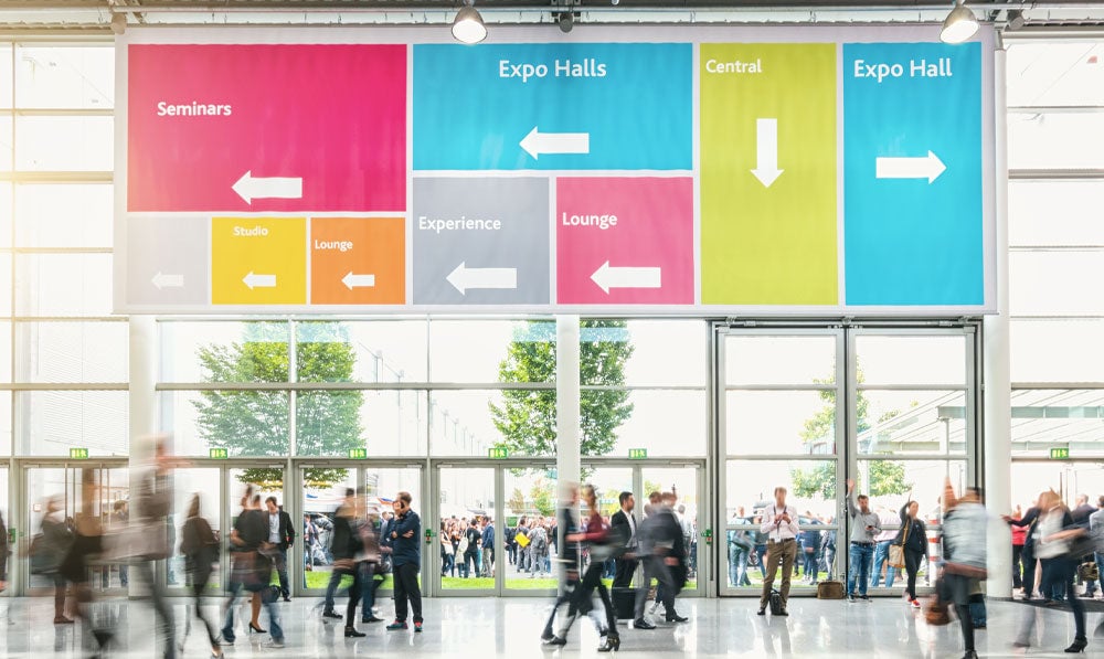 People navigating a trade show using overhead signs