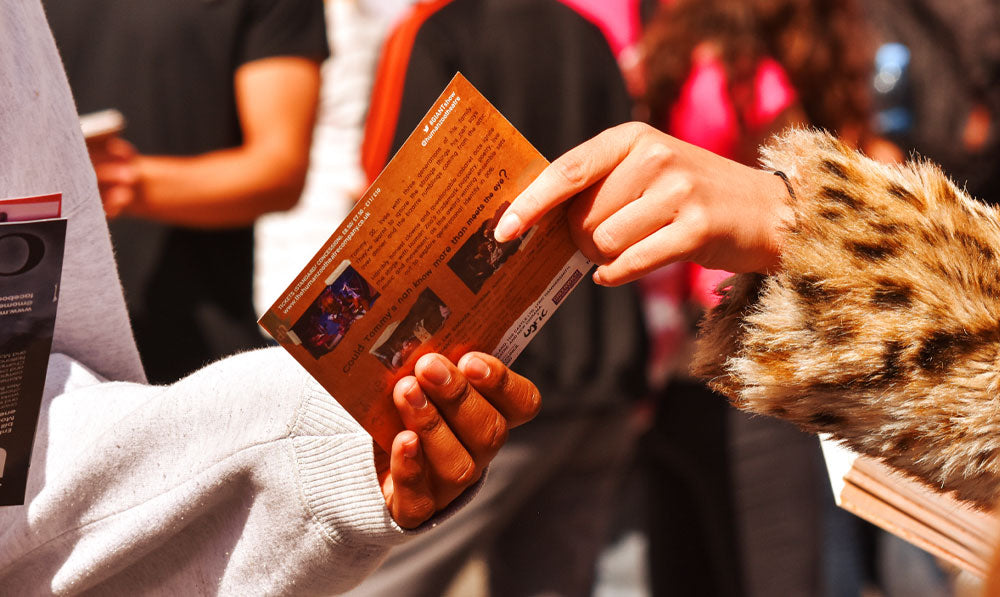 Temp worker sharing flyer with woman while outside