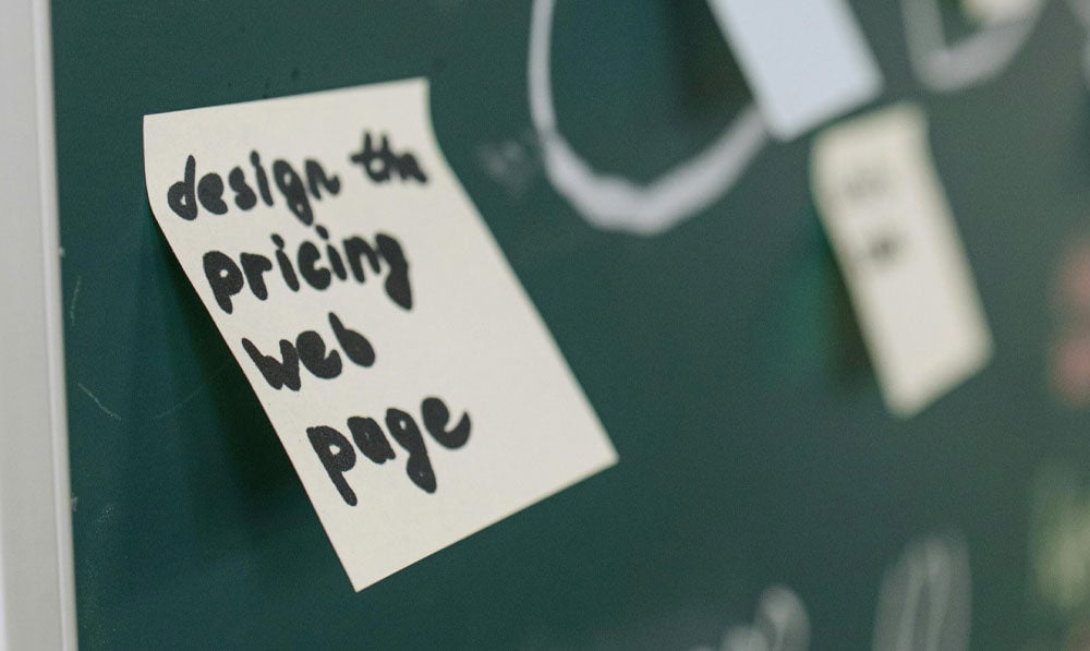 Closeup of "Design Price Page" on a sticky note