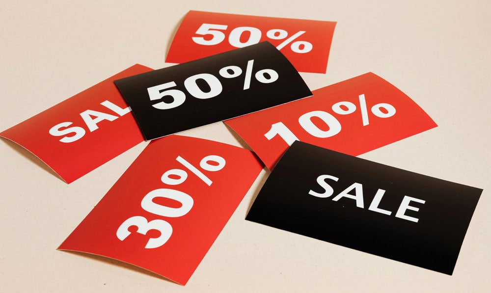 Sale and pricing signs laying together on ground