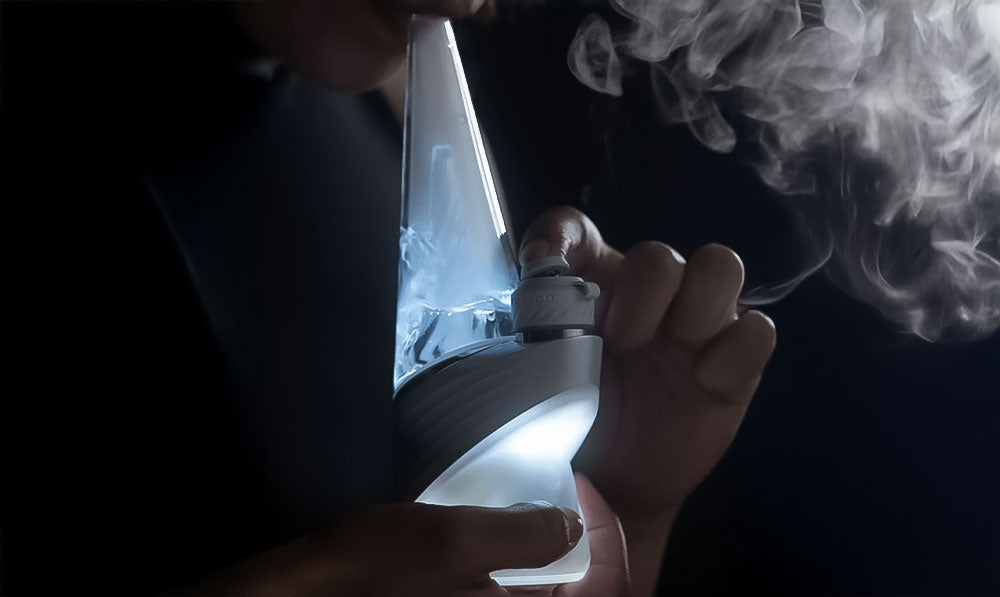 Man smoking Puffco Peak Pro Pearl in front of dark background