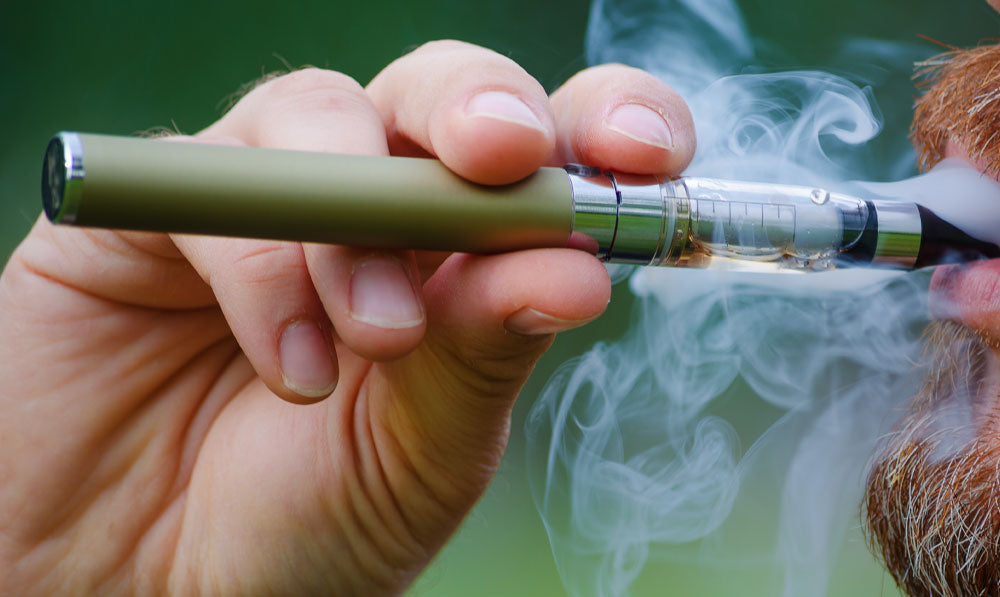 Man using 510 Thread Battery in front of grassy trail