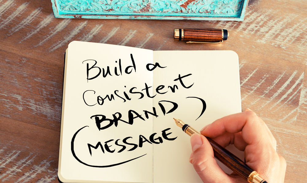A notepad and a pen reading "Build a Consistent Brand Message"