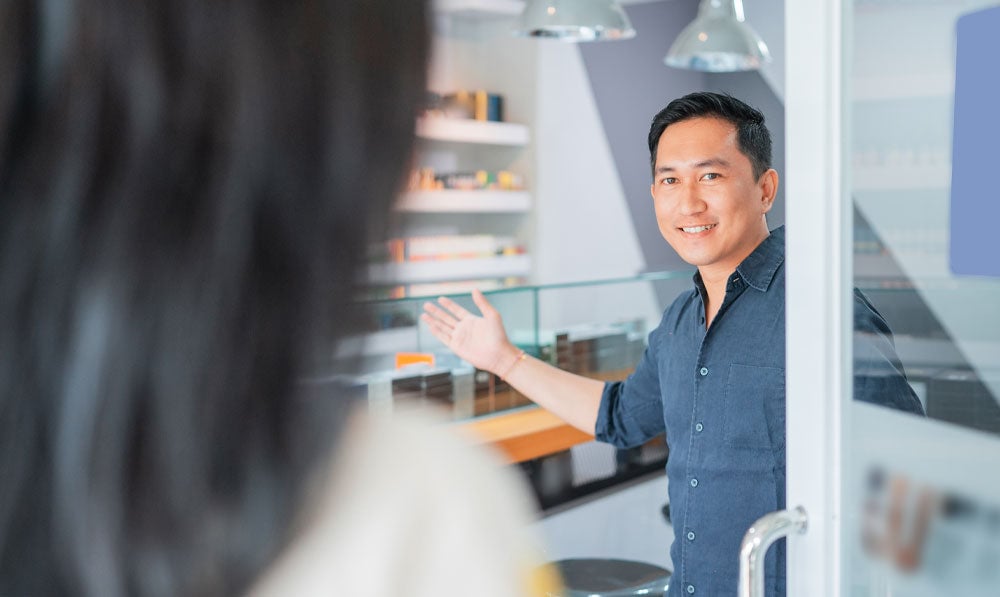 Shop owner welcoming new customer into store