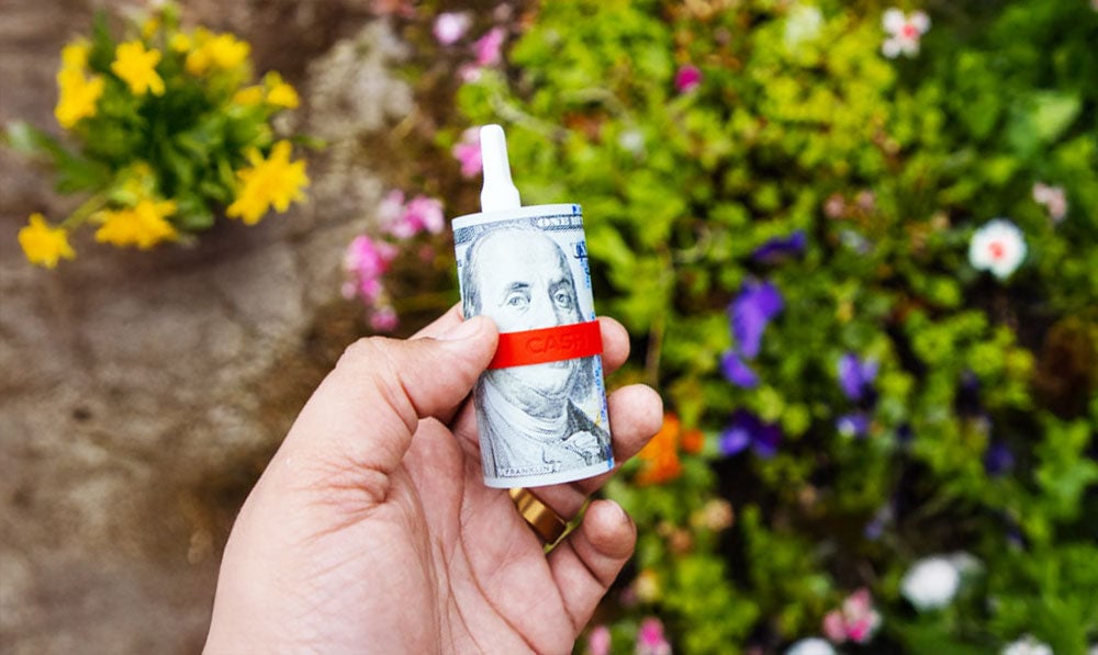Man holding Yocan Black Cash above spring flowers