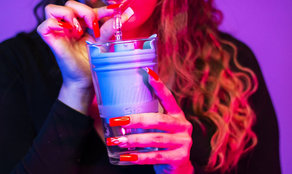 Woman holding Yocan Black Sip in front of purple studio background