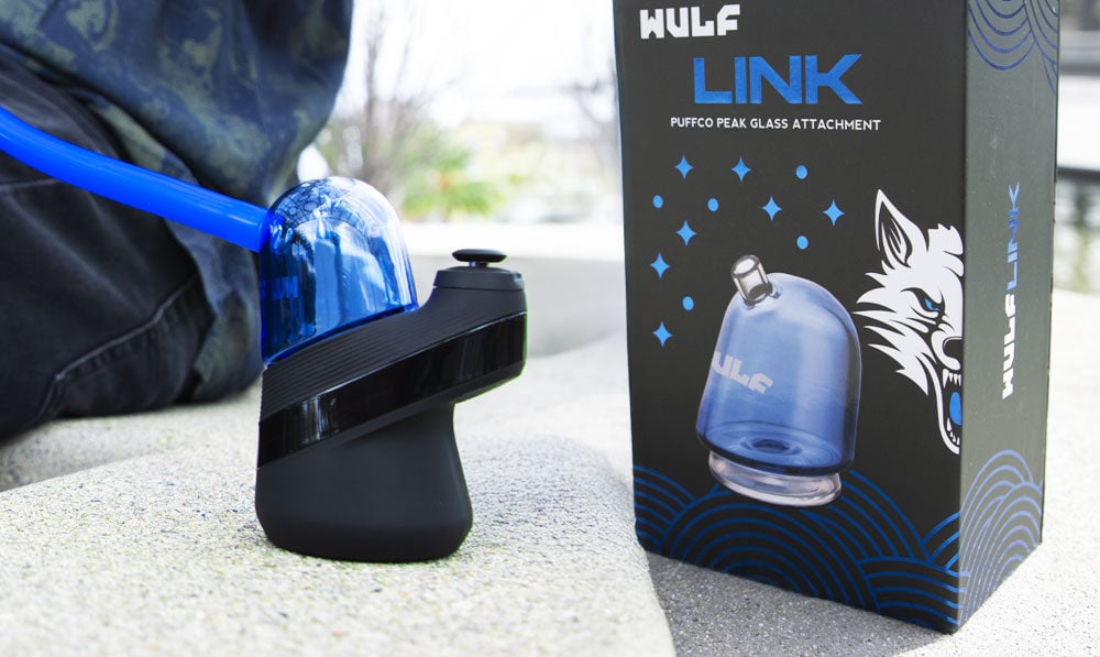 Wulf Link Puffco Attachment resting on concrete park wall with packaging nearby