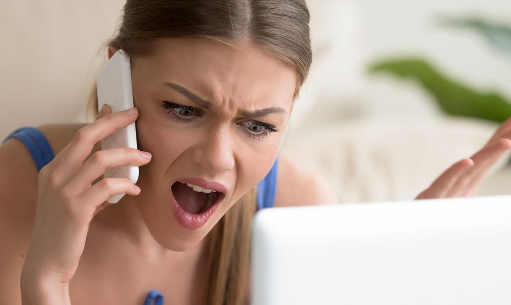 Unhappy woman on the phone with a laptop in front of her