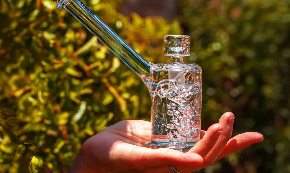 Person holding glass bubbler in use with water bubbling