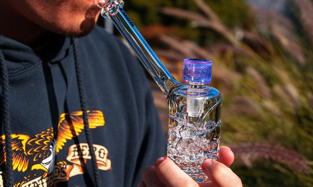 Man using glass bubbler outside
