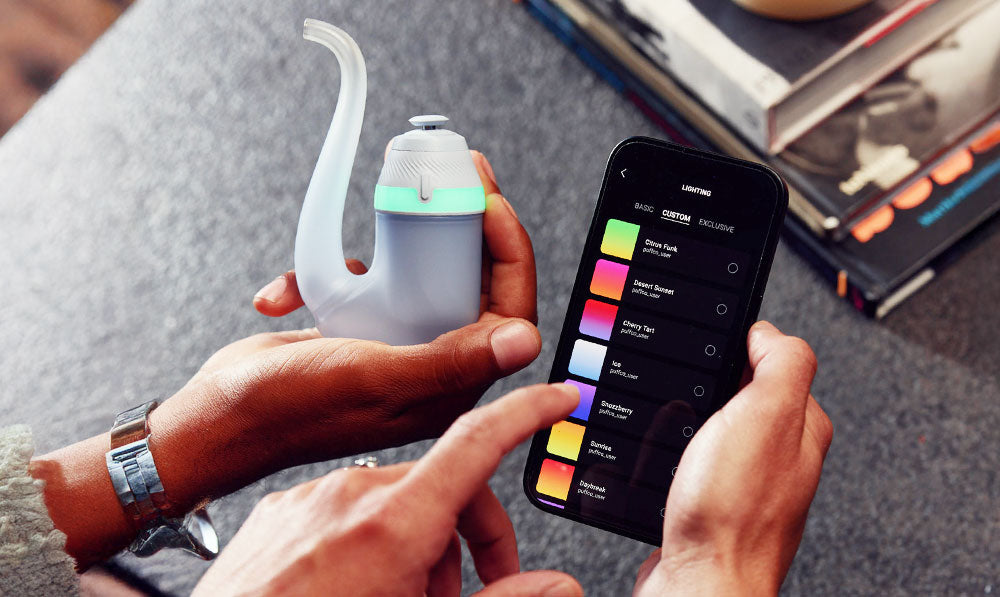 Hand holding Puffco New Proxy next to phone with Connect App
