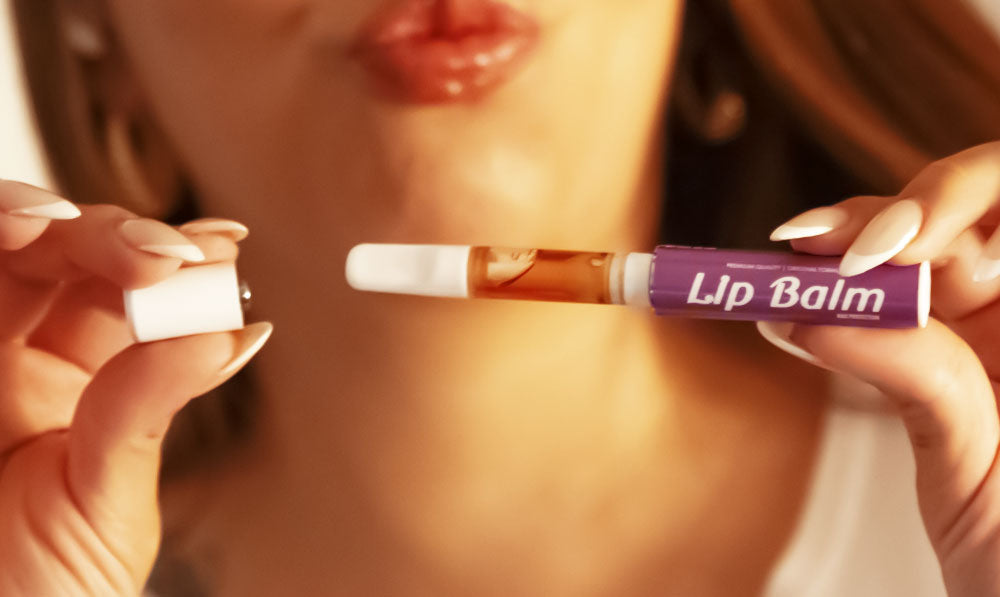 Woman puckering her lips and holding Smyle Chapstick Pen apart