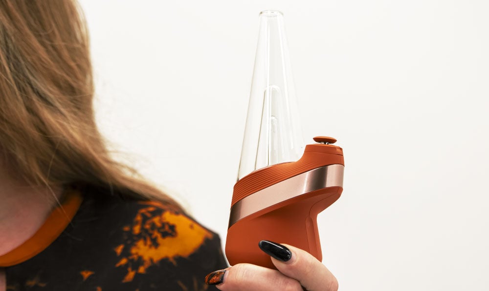 Woman holding Puffco New Peak Canyon in front of white wall