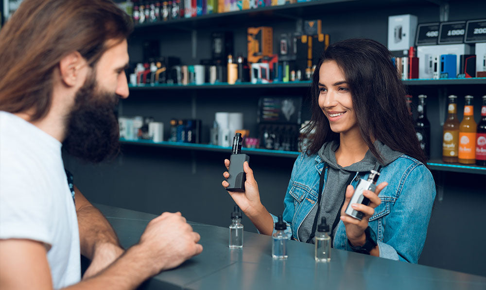 woman shop owner showing vaporizers to customer
