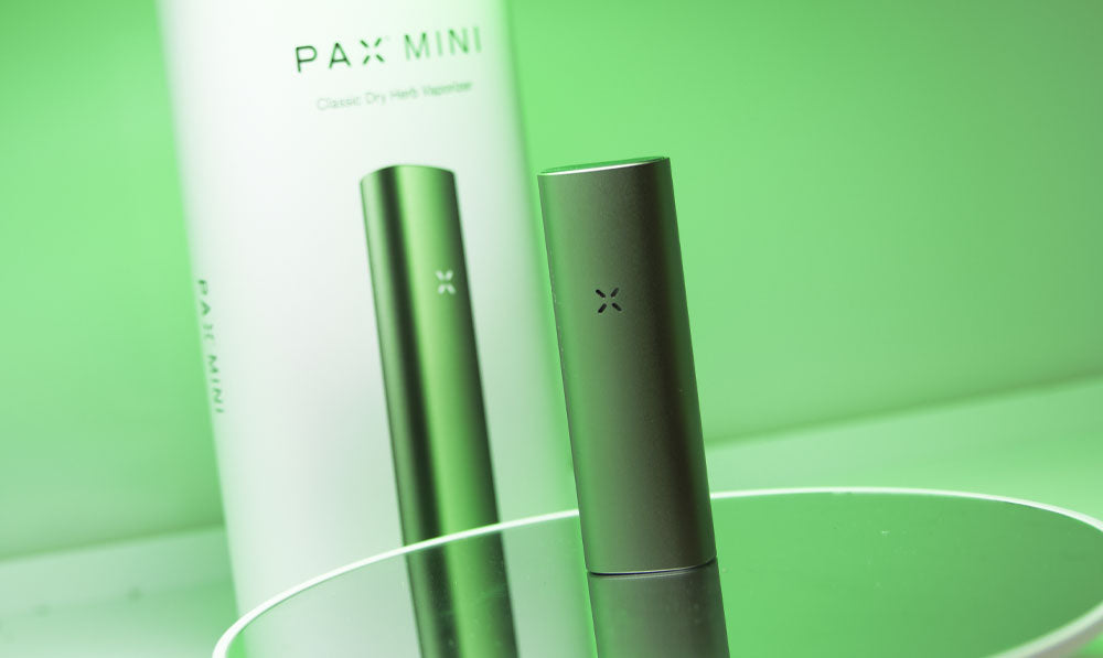 PAX Mini 2 on reflective surface with packaging and green lighting