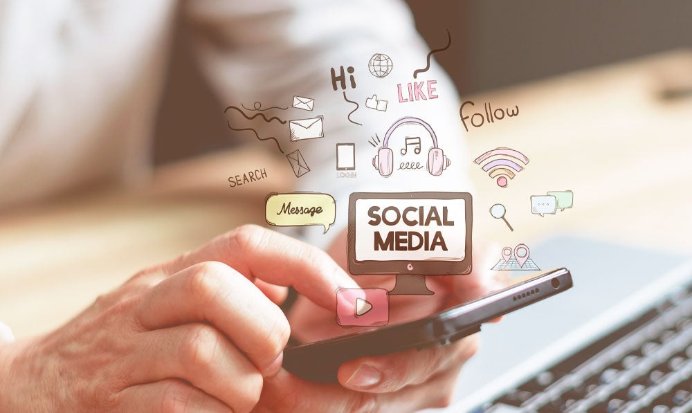 Person Holding Phone Near Laptop With Floating Social Media Icons