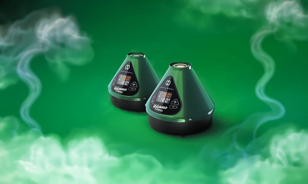 Storz & Bickel Evergreen Hybrid Volcano on green display with smoke clouds nearby