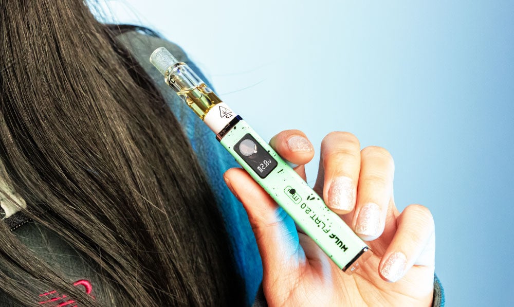 Closeup of woman holding Wulf Flat Mini 2.0 in front of teal/blue studio background