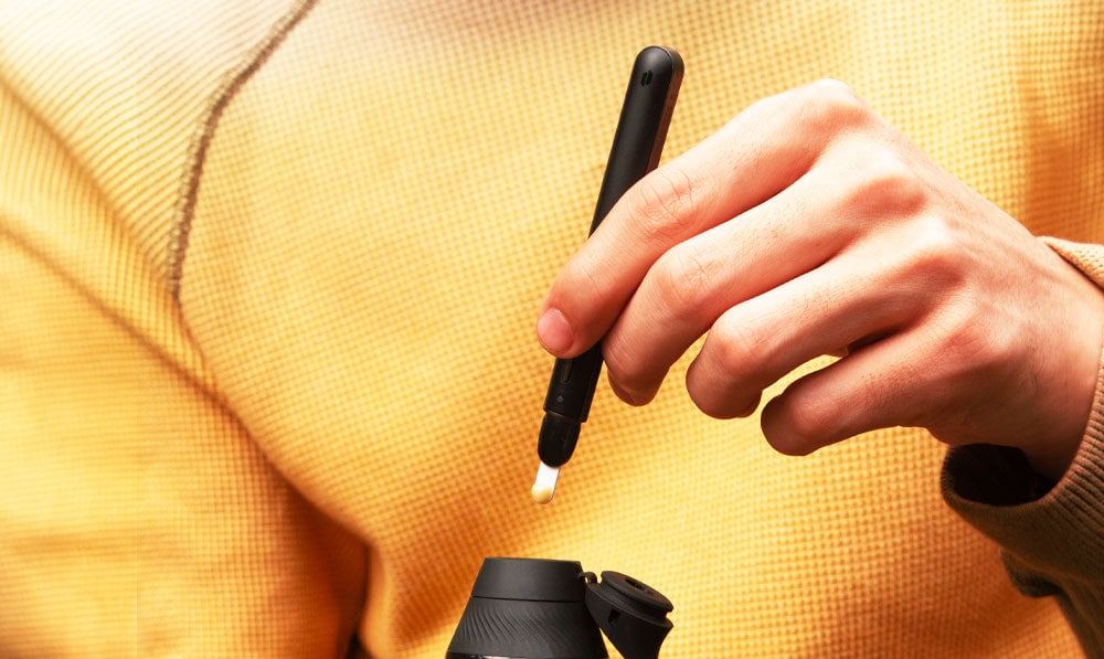 Man in yellow sweater holding Puffco New Hot Knife over Proxy core