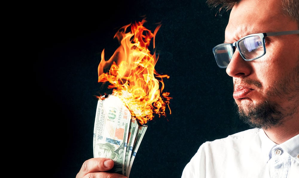 Upset man staring at burning money