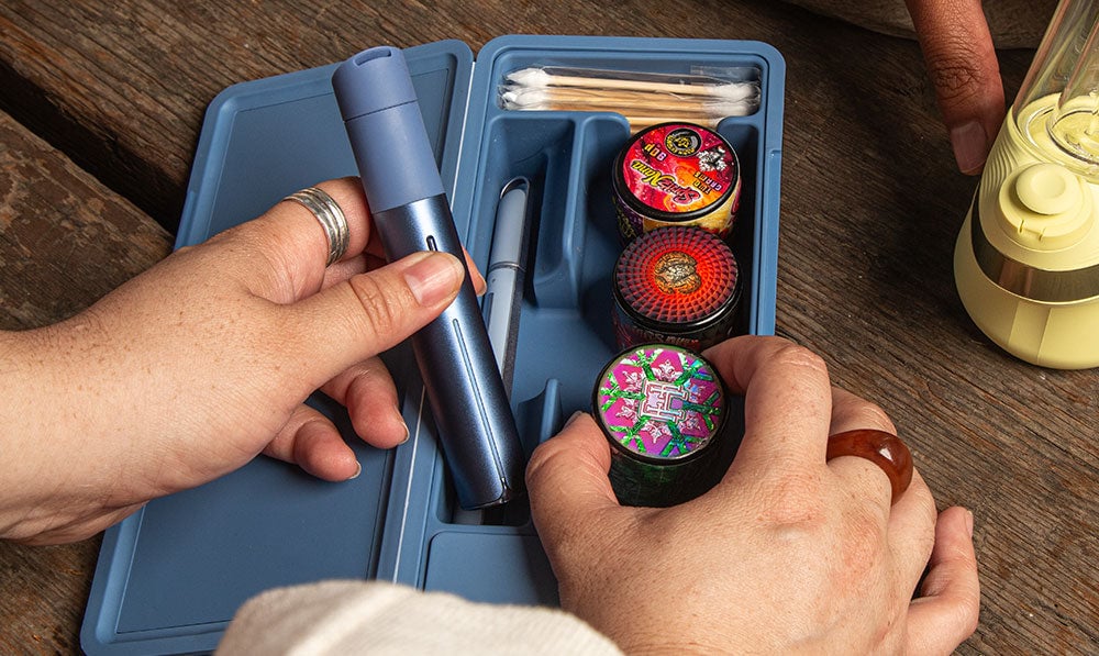hand holding Puffco Pivot Sapphire with accessories