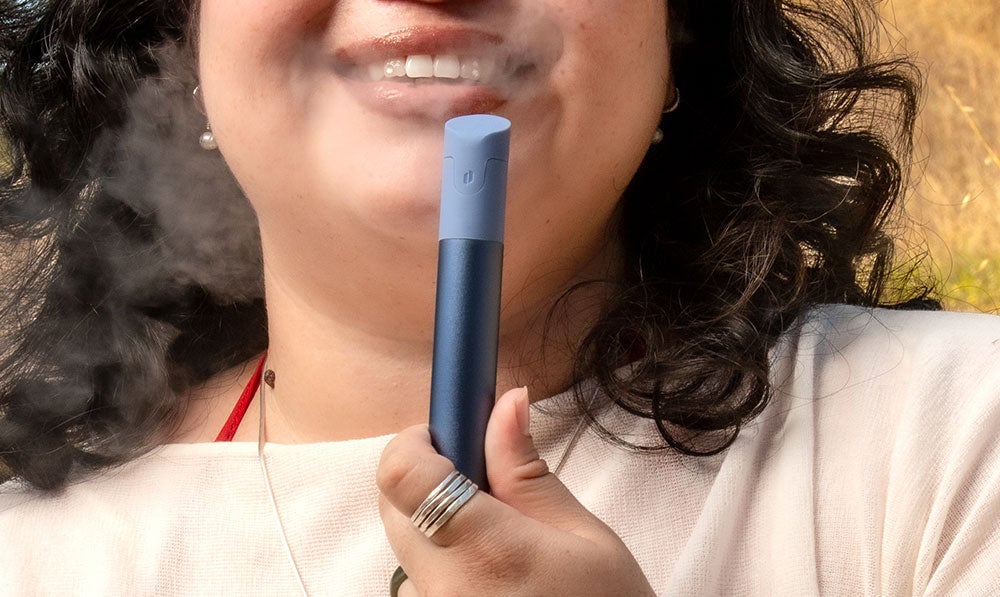 woman smiling using the Puffco Pivot Sapphire edition outdoors