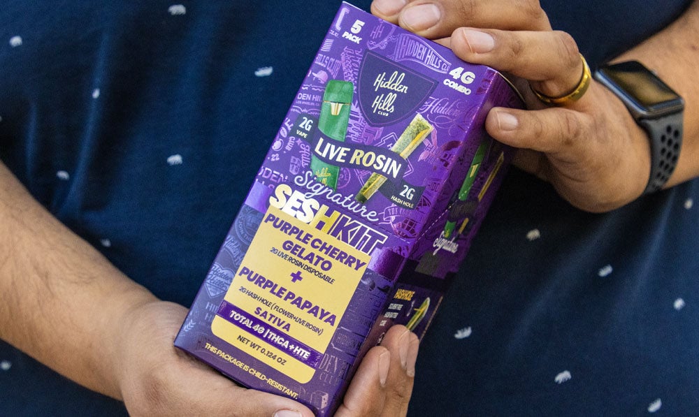 hidden hills preroll pack in purple man with blue shirt holding it in his hands