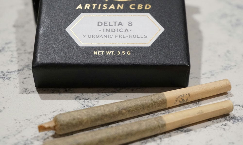 Artisan CBD Delta 8 indica package beside two pre rolls
