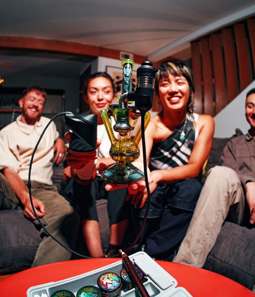 Group of people holding Puffco Link attached to waterpipe at a party