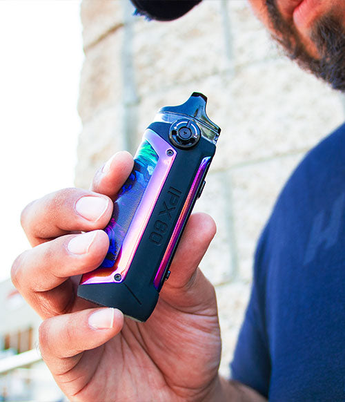 man in hat holding SMOK IPX80 near building