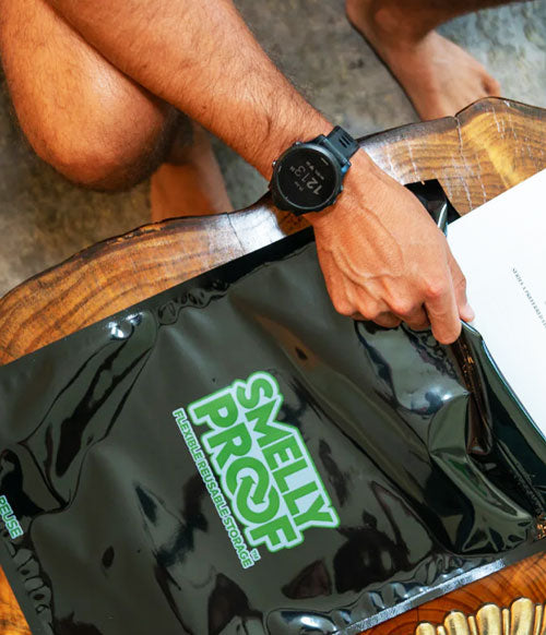 Smelly Proof bag on log table being inserted into backpack