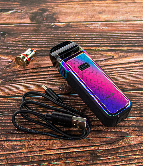 SMOK Nord X laying on wood table with coil and charger next to device