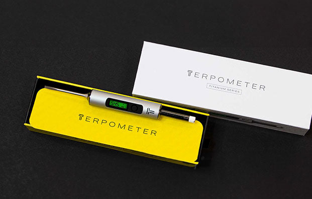 Terpometer laying down on black table with packaging