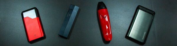 Wholesale Suorin Products Suorin Air, Edge, Vagon, and Air Plus lined up in a row on black table in florescent lighting