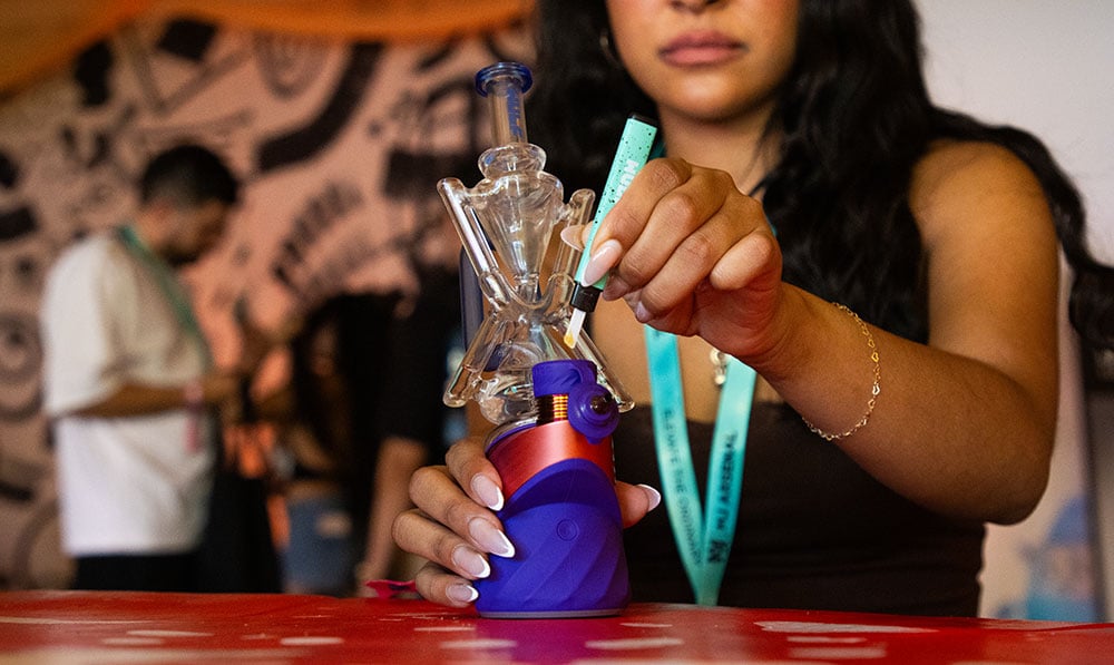 woman holding the Puffco Peak with Wulf Glass attachment and Wulf Slyce hot knife at Puffcon VIP lounge
